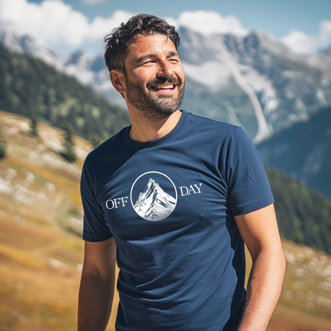 Lachender Mann im dunkelblauen Off Day T-Shirt vor schneebedeckten Gipfeln