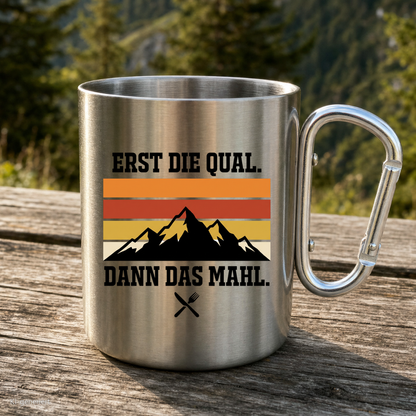 Karabinertasse von Kraxelgaudi mit Spruch Erst die Qual dann das Mahl steht auf Holz vor Bergkulisse