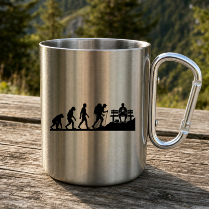 Karabinertasse von Kraxelgaudi mit Evolution des Wanderers steht auf Holz vor Bergkulisse