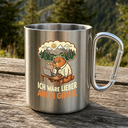 Karabinertasse von Kraxelgaudi mit Murmeltier und Spruch Ich wäre lieber aufm Gipfel steht auf Holz vor Bergkulisse