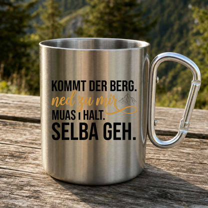Karabinertasse von Kraxelgaudi mit Spruch Kommt der Berg ned zu mir steht auf Holz vor Bergkulisse